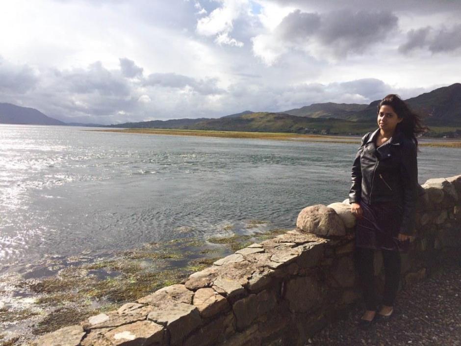 A girl standing with the mountains and water in the background