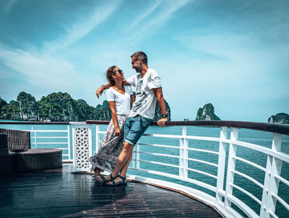 A couple posing against the blue water and green mountains as they travel with love