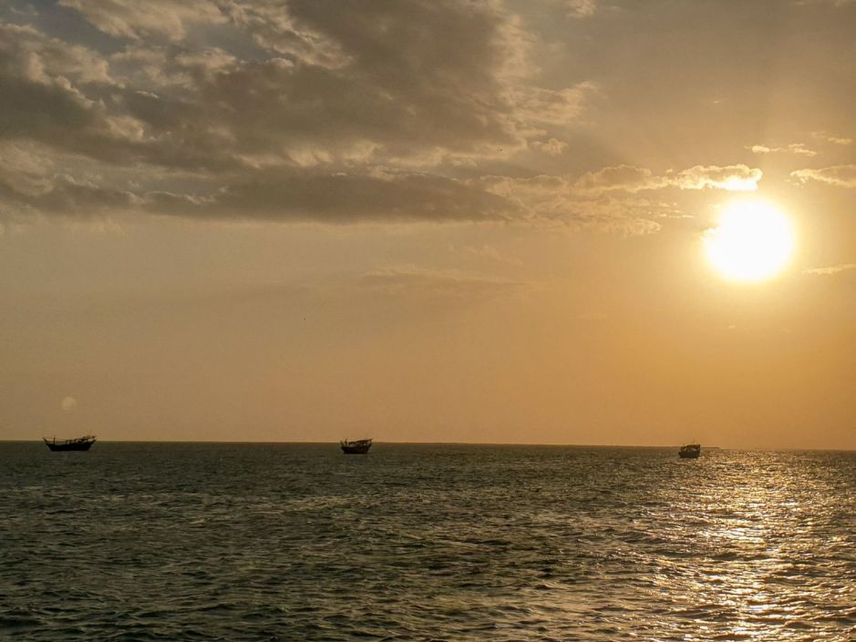 Small fishing boats in the sea during golden hour near Masirah Island