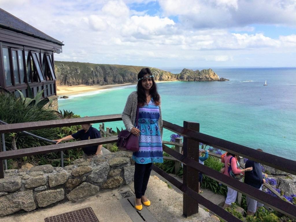 A girl standing with rocks of Minack Theatre and Celtic Sea in the background