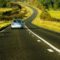 A car going on the road with greenery on both sides